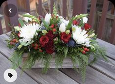 a wooden box filled with red and white flowers