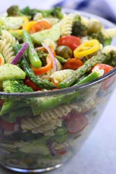 a glass bowl filled with pasta and vegetables