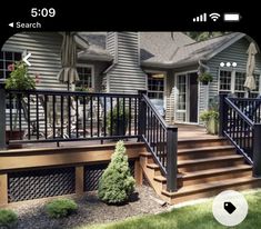 a wooden deck with black iron railings and hand rails in front of a house