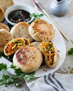 a white plate topped with rolls covered in toppings next to dipping sauce and chopsticks