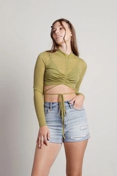 Elevate your style with the Helga Sheer Mock Neck Ruched Tie Crop Top in Green. This mock neck long-sleeve top features sheer material, wrap around ties, and an adjustable front ruched detail. This is photo-ready piece is great for festivals. Sheer Crop Top, Tie Crop Top, Girls Top, Crop Top Outfits