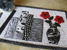 a black and white table mat with red flowers in a vase on top of it