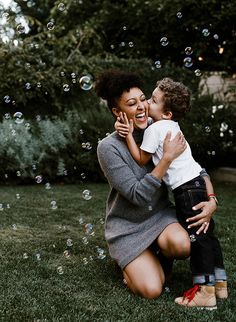 a woman kneeling down next to a little boy on top of a grass covered field