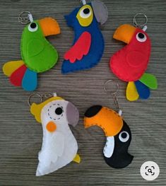 four different colored parrots are hanging from key chains