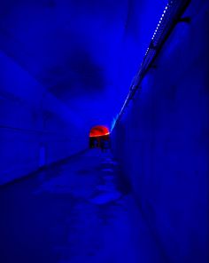 an empty tunnel with blue lighting and red light