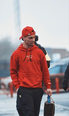 a man in a red hoodie is walking down the street with an umbrella and briefcase