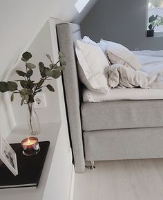 a bed sitting next to a window with a vase filled with flowers on top of it