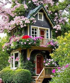 a small house with flowers growing on the roof and stairs leading up to it's second floor