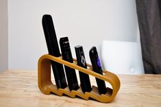 a cell phone holder with four remotes in it on a wooden table next to a window