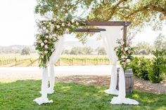 an outdoor wedding ceremony setup with white drapes and pink flowers on the arbors