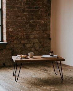 a wooden table topped with a cup of coffee and a plate of food next to a window