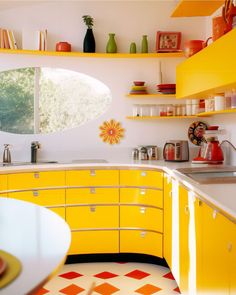 a kitchen with yellow cabinets and white counter tops is pictured in this image, there are vases on the shelves above the sink