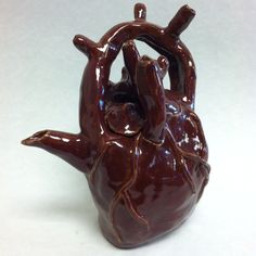 a brown ceramic heart shaped vase sitting on top of a white tablecloth covered floor