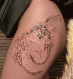 a woman's thigh with a dragon and fish tattoo on the side of her leg