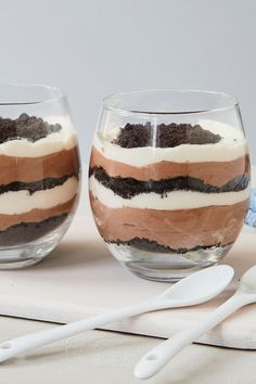 two glasses filled with dessert sitting on top of a table