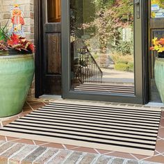 two large green planters with flowers in them on the front steps of a house