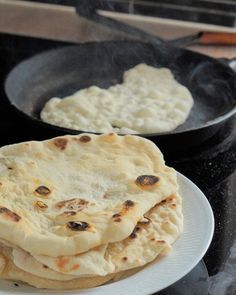 three flat breads sitting on top of a white plate next to a frying pan