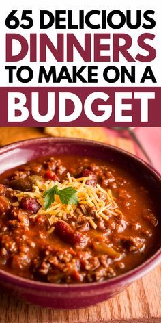 a red bowl filled with chili and cheese on top of a wooden table next to bread