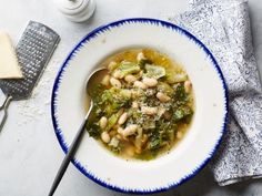 a white bowl filled with beans and greens on top of a blue and white plate