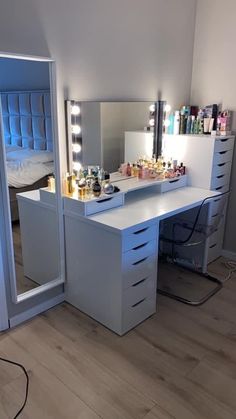 a white vanity with lighted lights and drawers in a small room next to a bed