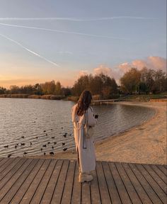 a woman standing on a pier looking at birds