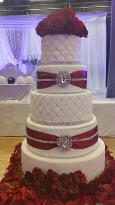 a three tiered wedding cake with red roses