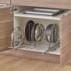 an open cabinet with many pots and pans in it