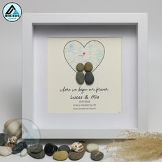 a white frame with some rocks in it and a couple's heart on the front