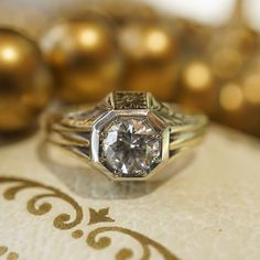 This Retro era engagement ring features a .71 carat Round Brilliant cut diamond and orange blossom engravings in 14 karat yellow gold. The sparkling near colorless diamond is bead set in the center of an octagon mounting. The sharp lines and romantic floral engravings give the geometric engagement ring an artistic look. From the profile, orange blossom engravings decorate the gallery rail, finished on a polished 14 karat yellow gold band. PRIMARY STONE Stone: Genuine Natural Diamond Measurements Diamond White 14k Gold Heirloom Wedding Ring, Heirloom 14k Gold Diamond White Wedding Ring, Timeless Diamond Cut Engraved Ring For Anniversary, Heirloom Diamond Ring With Rose Cut Diamonds For Anniversary, Heirloom Yellow Gold Wedding Ring With Single Diamond, Heirloom Wedding Diamond Ring With Single Diamond, Timeless Engraved Diamond Cut Ring For Anniversary, Heirloom Rose Cut Diamond Ring For Anniversary, Heirloom Diamond Cut Jewelry For Anniversary