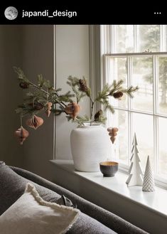 a white vase sitting on top of a window sill next to a christmas tree