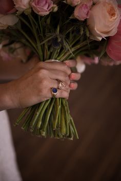 a close up of a person holding a bouquet of flowers with rings on their fingers