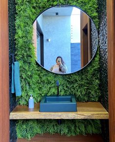 a mirror that is on the side of a shelf in front of a plant wall