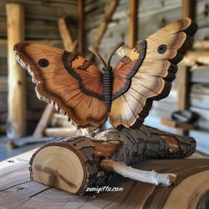 a butterfly sculpture sitting on top of a piece of wood