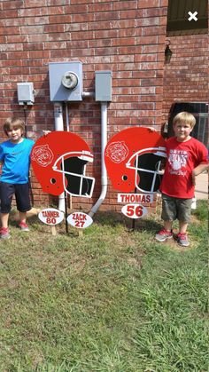 two young boys standing next to each other in front of a brick wall with signs