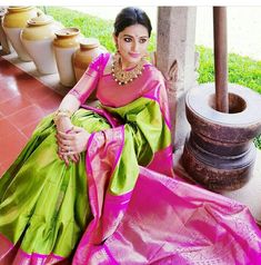 a woman in a pink and green sari sitting on the ground next to potted plants