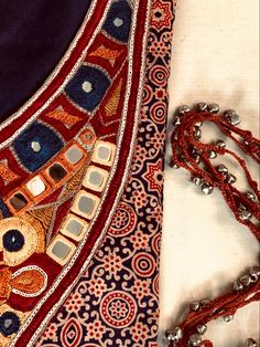 a close up of a piece of cloth with beads on the bottom and an orange beaded chain