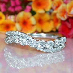 a wedding band with three rows of diamonds on it, sitting next to some flowers