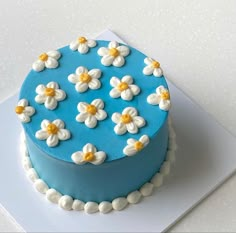 a blue cake with white and yellow flowers on it