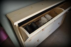 a wooden shoe rack with two pairs of shoes in it and the bottom drawer is open