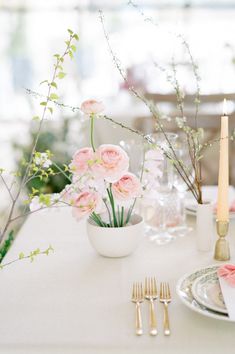 the table is set with pink flowers and gold cutlery, along with silverware