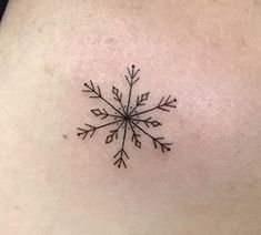 a small snowflake tattoo on the back of a woman's shoulder and neck