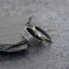 two wedding rings sitting on top of a rock next to each other with diamonds in them