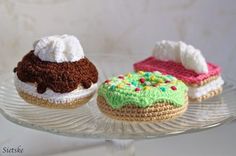 three crocheted cupcakes sitting on top of a glass plate