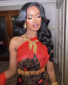 a woman in a red and gold dress with long black hair wearing an elaborate necklace