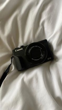 a black camera sitting on top of a white sheet