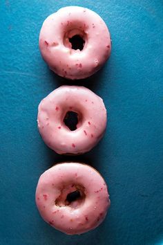 three pink donuts sitting on top of a blue plate