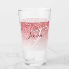 a shot glass with the name jesus on it in red and pink glitters, sitting on a marble surface