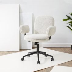 a white office chair sitting on top of a wooden floor next to a potted plant