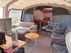 the inside of a tent with couches, chairs and televisions in front of it