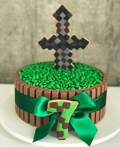 a cake decorated with green and brown icing on a white plate next to a wooden cross